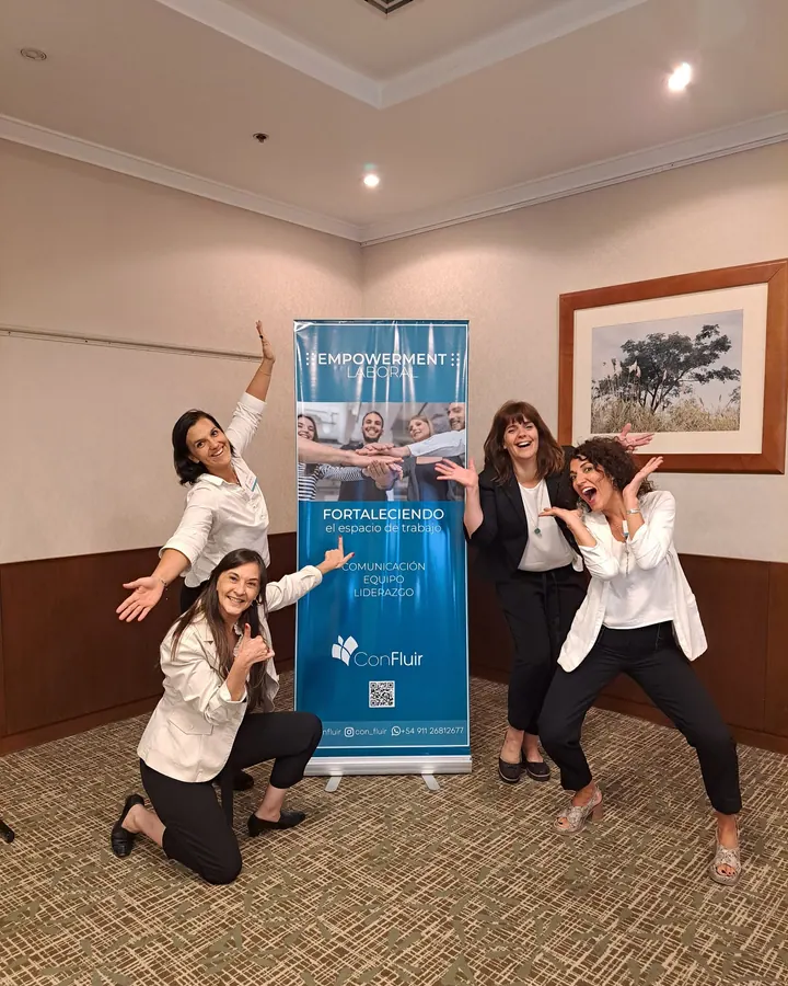 Mariana, Cecilia y colegas posando con alegría junto al banner de Confluir